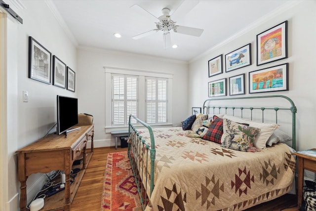 bedroom featuring a barn door, wood finished floors, a ceiling fan, baseboards, and ornamental molding