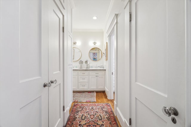 bathroom featuring double vanity, ornamental molding, wood finished floors, a sink, and recessed lighting