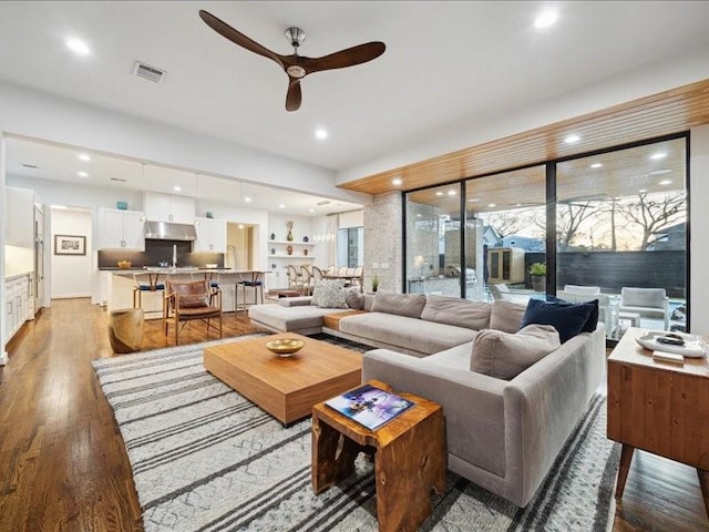 living room featuring a ceiling fan, visible vents, wood finished floors, and recessed lighting