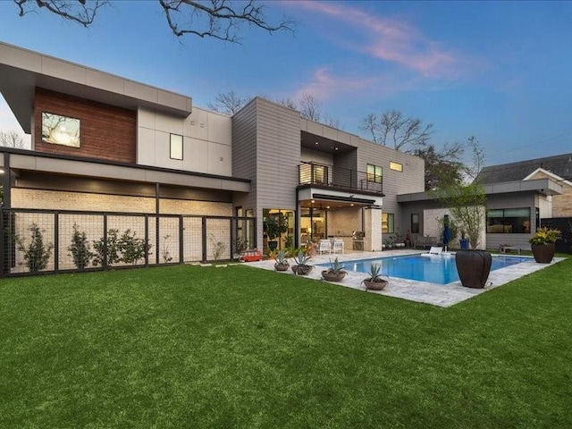 rear view of house featuring a balcony, a patio area, fence, and a yard