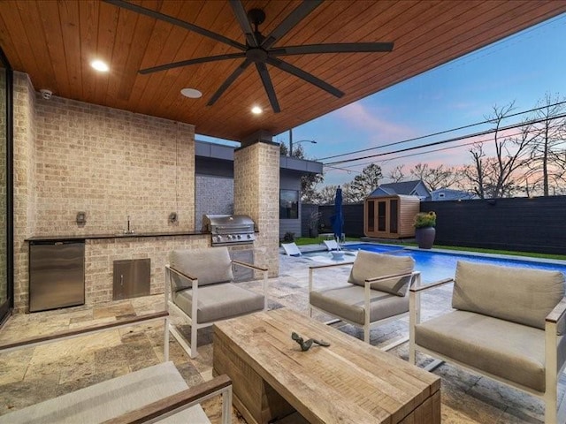 patio terrace at dusk featuring a fenced in pool, area for grilling, an outbuilding, a grill, and fence