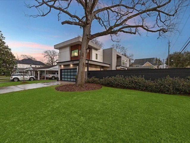 yard at dusk with driveway and an attached garage