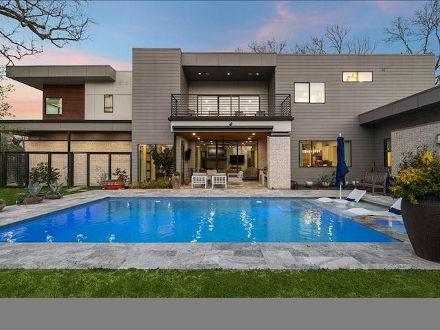 back of property with a fenced in pool, an outdoor hangout area, a patio area, fence, and a balcony