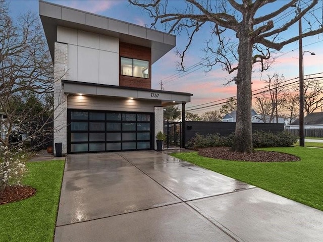 contemporary house featuring concrete driveway, brick siding, a yard, and an attached garage