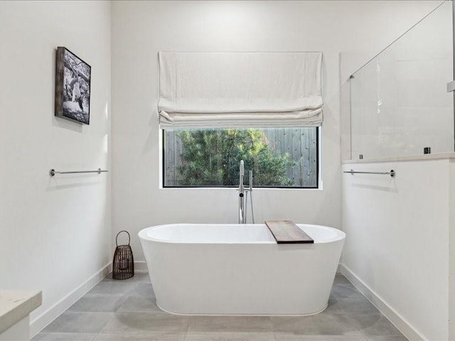 bathroom with a soaking tub and baseboards