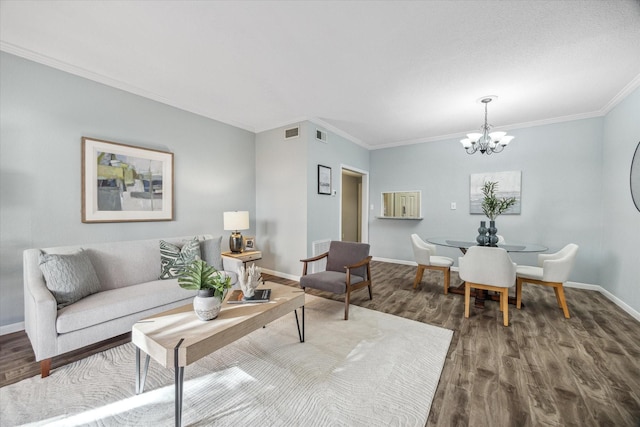 living room featuring a notable chandelier, wood finished floors, visible vents, baseboards, and crown molding