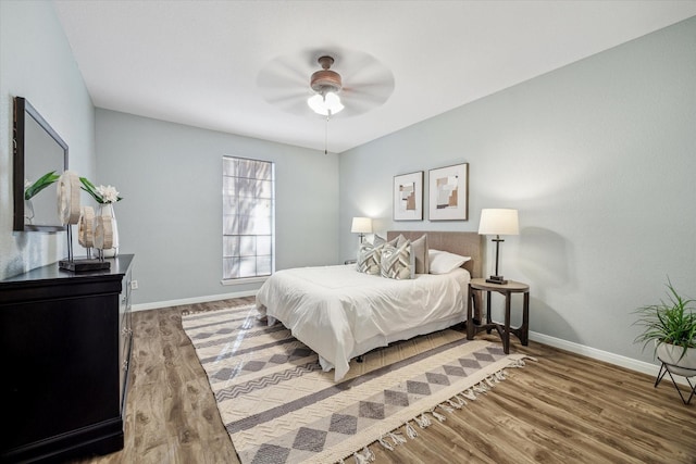 bedroom with a ceiling fan, baseboards, and wood finished floors