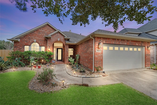 ranch-style home with driveway, a garage, a lawn, roof with shingles, and brick siding