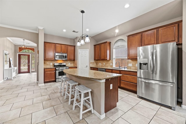 kitchen with visible vents, arched walkways, a kitchen island, brown cabinets, and stainless steel appliances