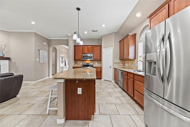 kitchen with arched walkways, light stone counters, a center island, stainless steel appliances, and light tile patterned flooring