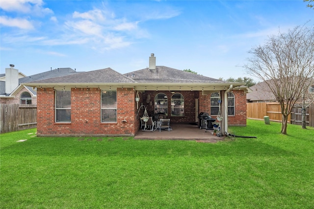 rear view of house featuring a patio area, a fenced backyard, a lawn, and brick siding