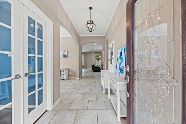 entrance foyer featuring light tile patterned floors, baseboards, arched walkways, ornamental molding, and french doors