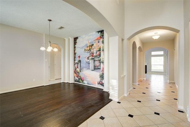 interior space with light wood-style flooring, visible vents, a chandelier, and baseboards