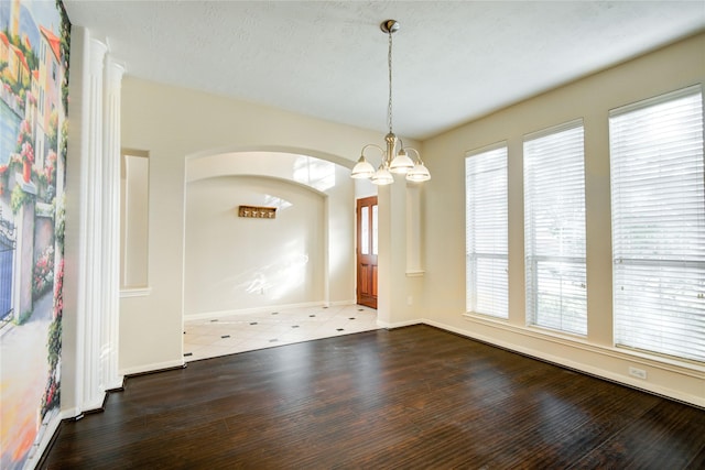 unfurnished dining area with baseboards, wood finished floors, and an inviting chandelier