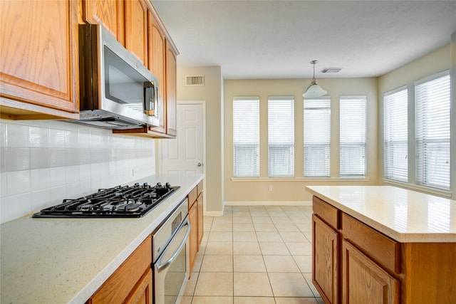 kitchen with stainless steel appliances, brown cabinetry, visible vents, and light tile patterned floors