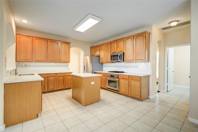 kitchen with arched walkways, stainless steel appliances, light countertops, backsplash, and a sink