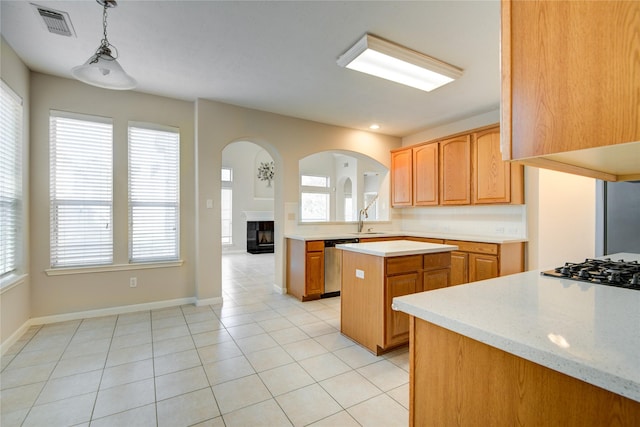 kitchen featuring visible vents, a kitchen island, light countertops, stainless steel dishwasher, and a sink