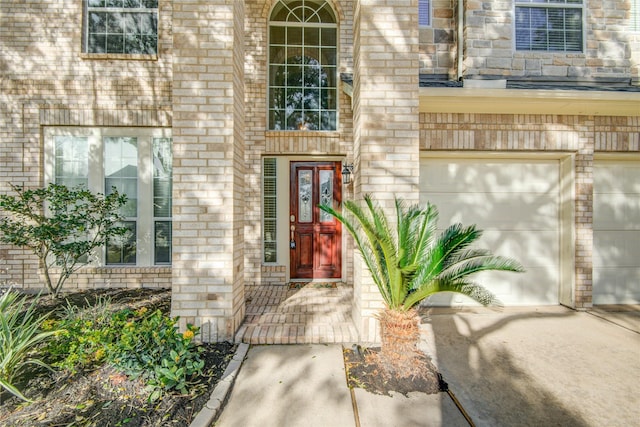 view of exterior entry featuring a garage and brick siding