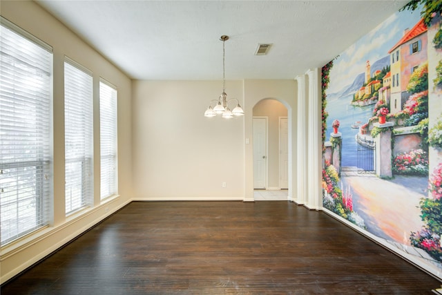 unfurnished dining area featuring a healthy amount of sunlight, a notable chandelier, visible vents, and wood finished floors