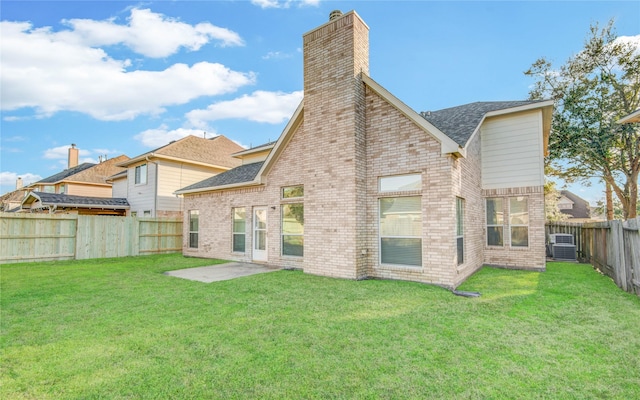 back of house featuring brick siding, a lawn, and a fenced backyard