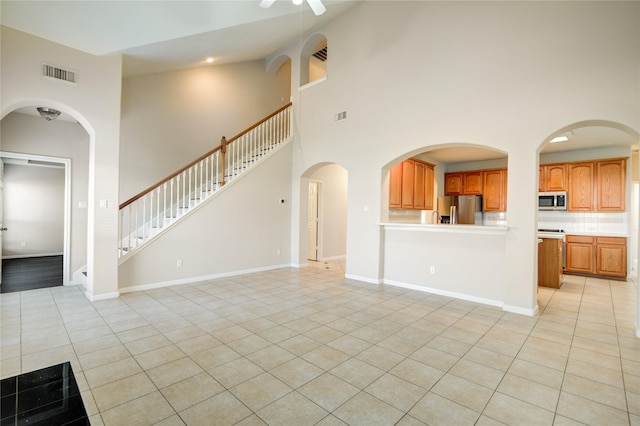 unfurnished living room featuring light tile patterned floors, baseboards, stairs, and visible vents