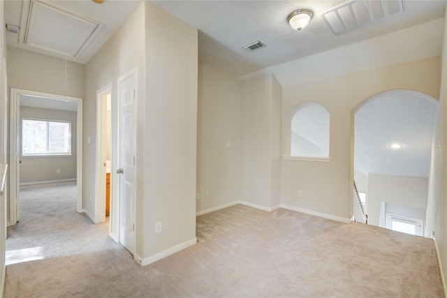 empty room with attic access, visible vents, and light carpet