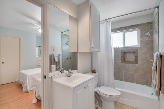 ensuite bathroom featuring ceiling fan, toilet, shower / tub combo, wood finished floors, and vanity