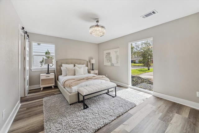 bedroom with multiple windows, wood finished floors, visible vents, and access to exterior