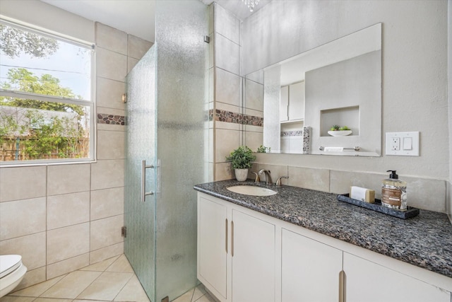 bathroom featuring toilet, tile patterned floors, vanity, a shower stall, and tile walls