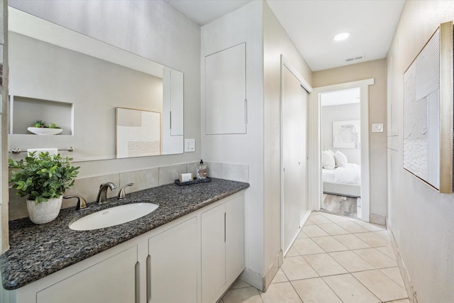 ensuite bathroom featuring ensuite bathroom, vanity, baseboards, visible vents, and tile patterned floors