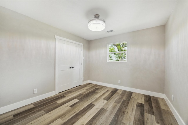 spare room featuring baseboards, visible vents, and wood finished floors