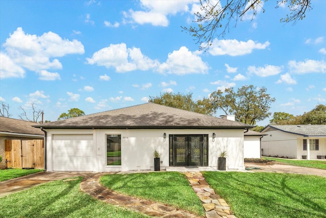 rear view of house featuring roof with shingles, a yard, stucco siding, an attached garage, and driveway