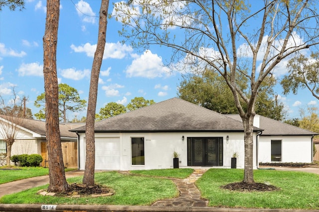 view of front facade with an attached garage, a shingled roof, a front lawn, and stucco siding