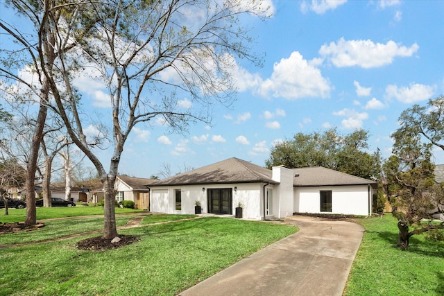 view of front of property with a chimney, stucco siding, a garage, driveway, and a front lawn