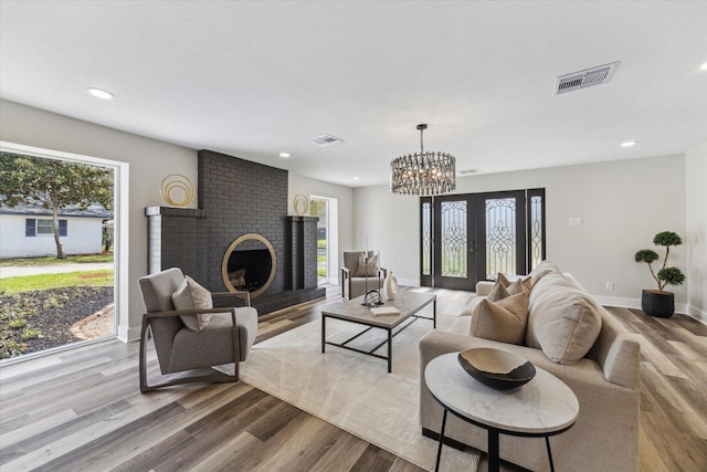 living room with baseboards, a fireplace, visible vents, and wood finished floors