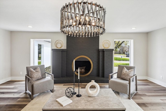 sitting room featuring a brick fireplace, baseboards, and wood finished floors