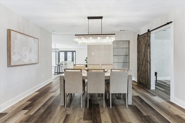 dining space featuring a chandelier, a barn door, dark wood finished floors, and baseboards