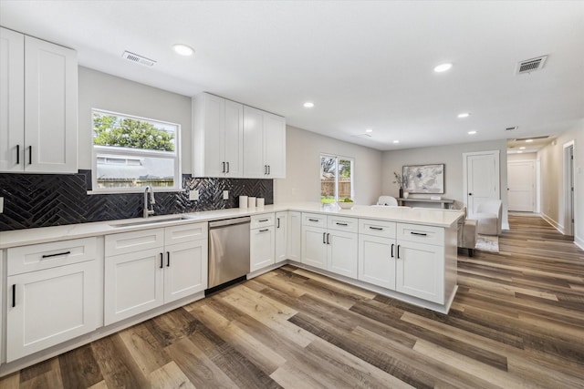 kitchen with visible vents, dishwasher, a peninsula, light countertops, and a sink