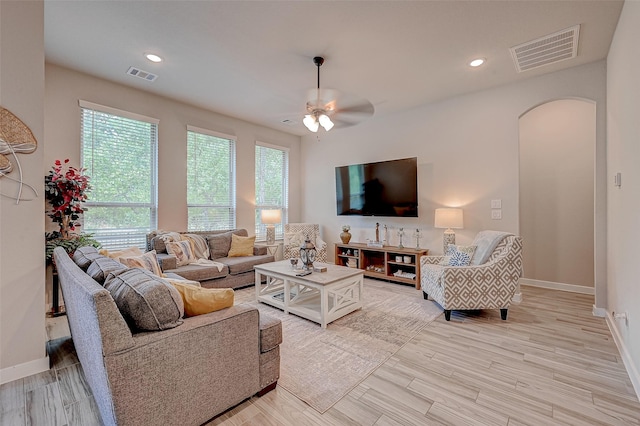 living room with arched walkways, visible vents, light wood finished floors, and recessed lighting