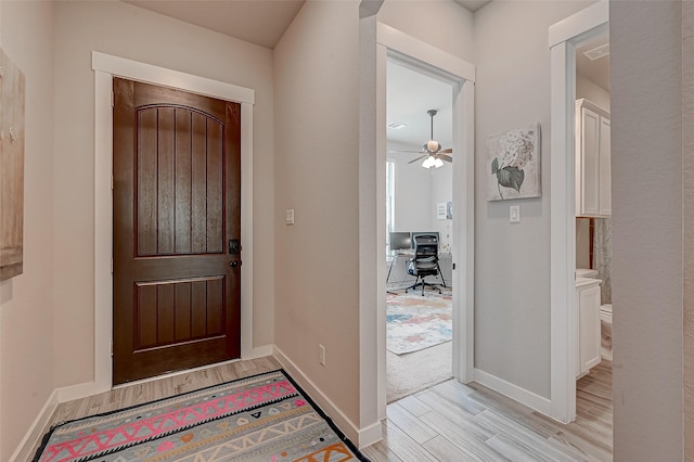 foyer entrance with a ceiling fan, baseboards, and light wood finished floors