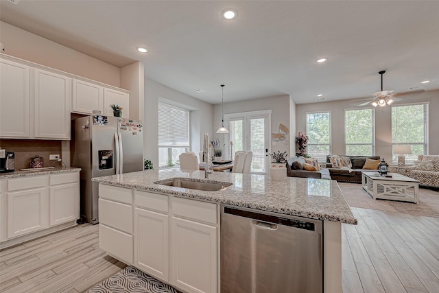 kitchen featuring a center island with sink, appliances with stainless steel finishes, open floor plan, white cabinets, and a sink