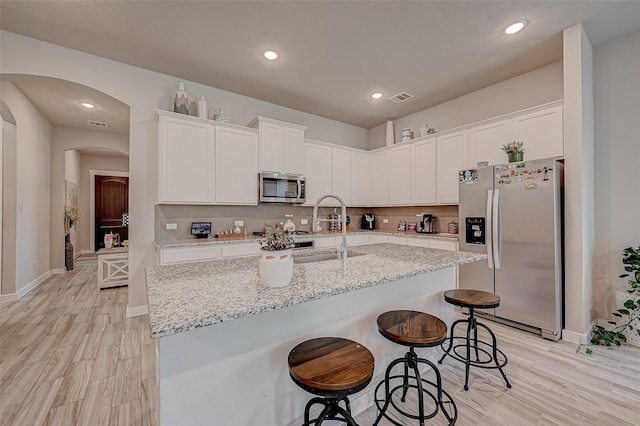 kitchen with visible vents, decorative backsplash, appliances with stainless steel finishes, white cabinetry, and a sink