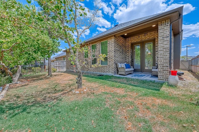 back of property with fence private yard, brick siding, a yard, french doors, and a patio area