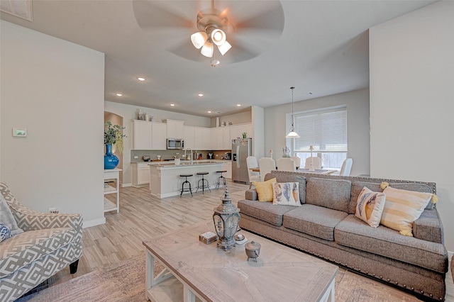 living area with light wood finished floors, baseboards, visible vents, a ceiling fan, and recessed lighting