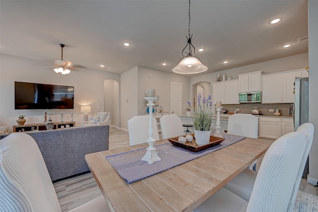 dining space with arched walkways, a ceiling fan, light wood-style flooring, and recessed lighting