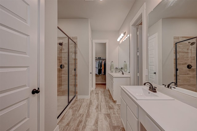 bathroom featuring a sink, a shower stall, a spacious closet, and two vanities