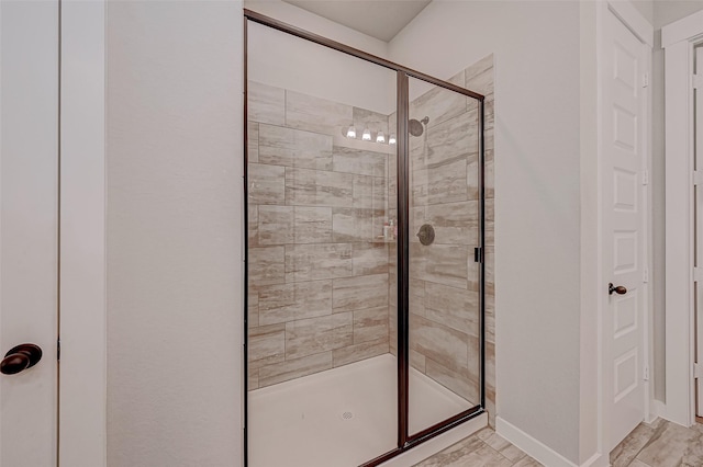 bathroom with a shower stall and baseboards