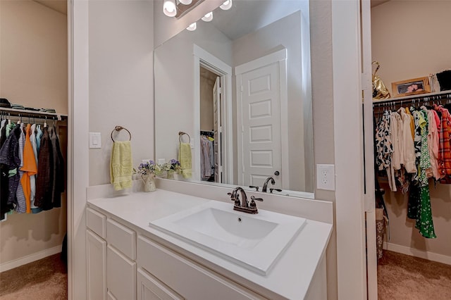 bathroom featuring a walk in closet, vanity, and baseboards