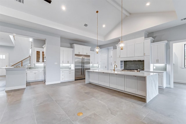 kitchen with high vaulted ceiling, high end fridge, a large island with sink, and a sink