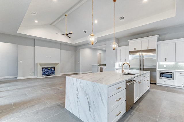 kitchen with tasteful backsplash, visible vents, built in refrigerator, a fireplace, and a sink